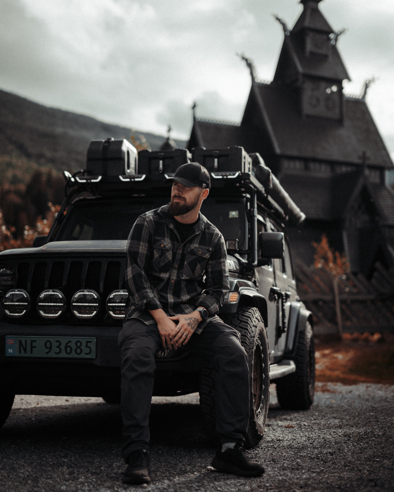 Tord sitting on the front of the Jeep in front of a stave church