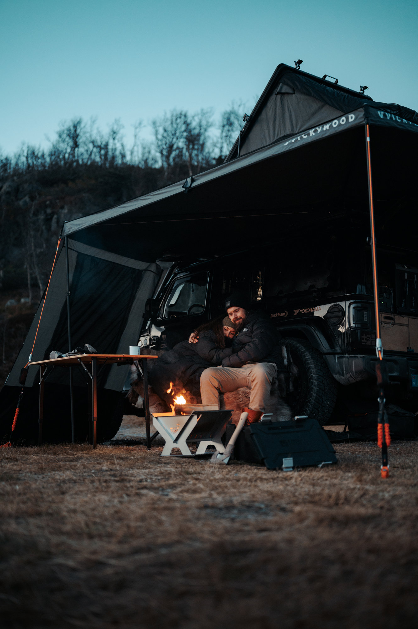 Tord and Eleni by a fire under the awning